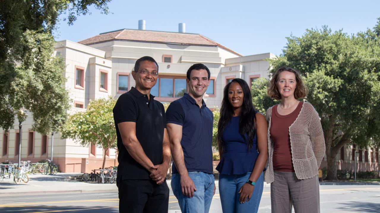 A group of male and female faculty and students standing in front of Green Hall on campus