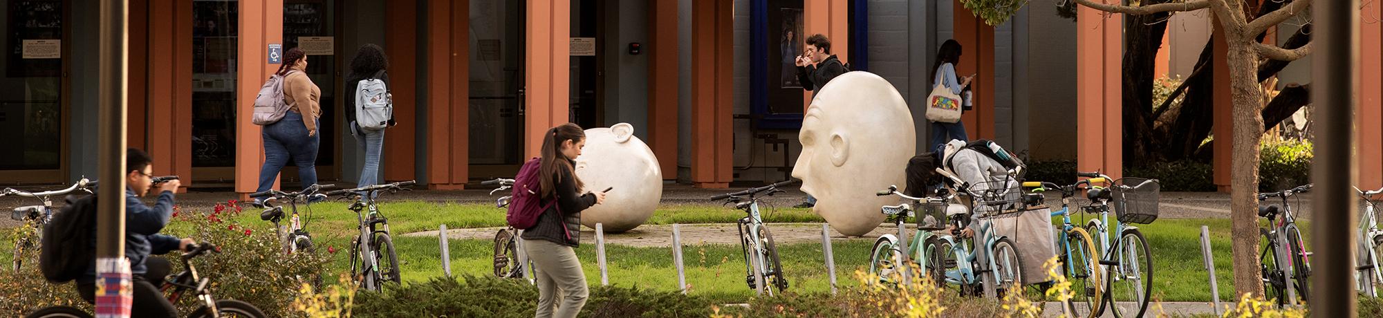 Students outside near the egghead sculptures outdoors