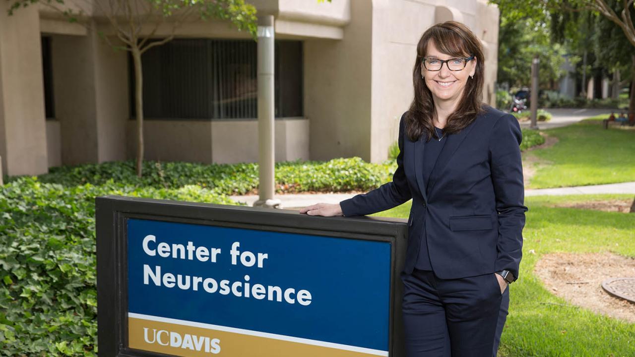 As director of the Center for Neuroscience, McAllister oversees roughly 25 labs housed at the interdisciplinary center, which is dedicated to understanding brain function in health and in illness throughout the lifespan. David Slipher/UC Davis picture of kim next to the center for neuroscience sign